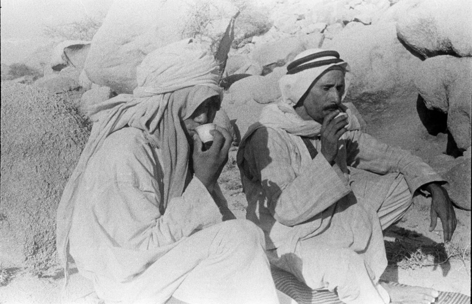 شاب ورجل يحتسيان القهوة قرب السيل الكبير.